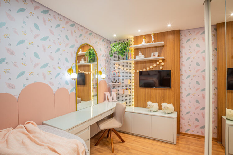 Quarto de menina em tons de rosa claro e verde com a presença de armários planejados e madeira.